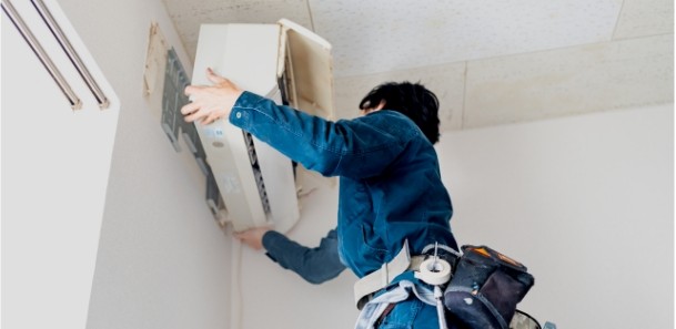 エアコンを取り外す作業員